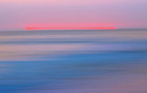Abstract image created of a pink sun setting over the Pacific Ocean in Laguna Beach, CA, using long exposure and intentional camera movement